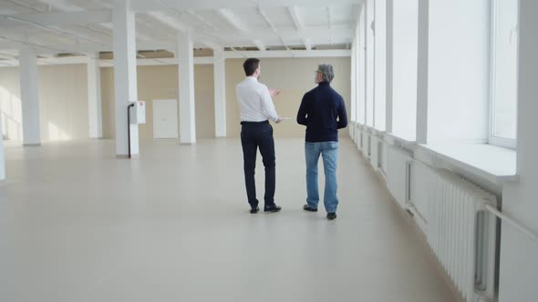 Realtor Walks Around and Shows Client Rented Office Space Back View