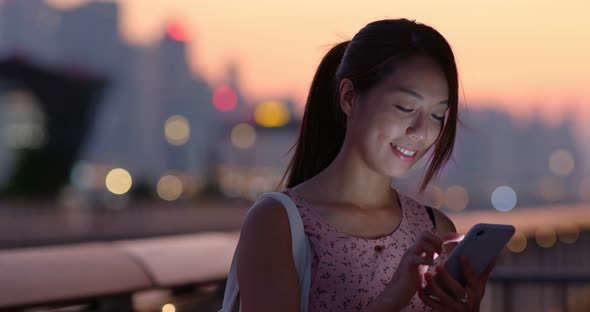 Woman use of mobile phone at beautiful sunset time