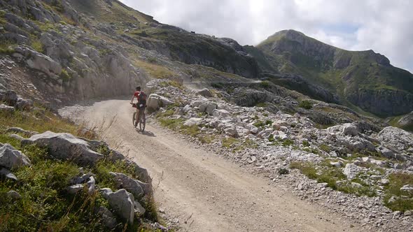 A man mountain biking on a European mountainside biking trail.