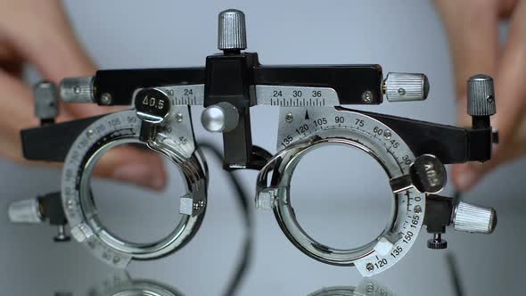 Hands Putting Optical Trial Frame on Table, Ophthalmic Testing Device Close-Up