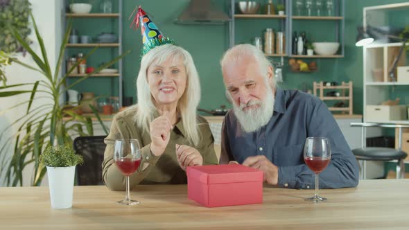 A Woman Enthusiastically Opens a Box With a Gift While Chatting