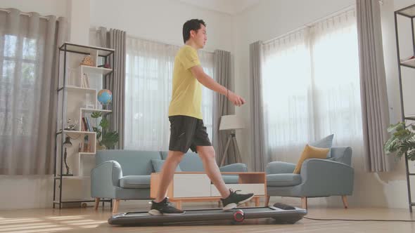 Side View Of Asian Man Training On Walking Treadmill At Home