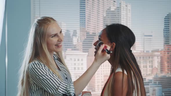 Close-up of Make-up Artist Applying Makeup on Black Model with Skyscrapers in the Background