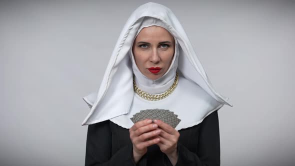 Portrait of Mysterious Woman in Nun Costume Holding Playing Cards Smiling and Looking Up