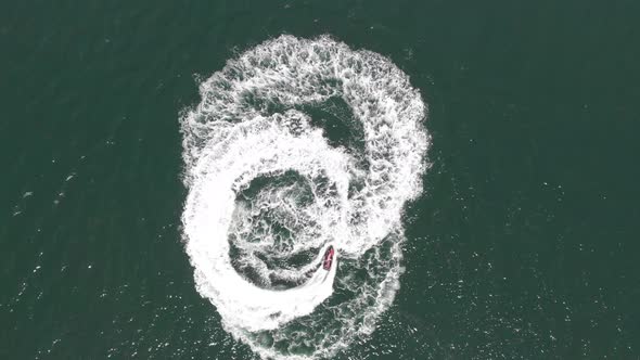 Powerful jet ski makes a figure-eight pattern in the water as an overhead drone adds excitement rota