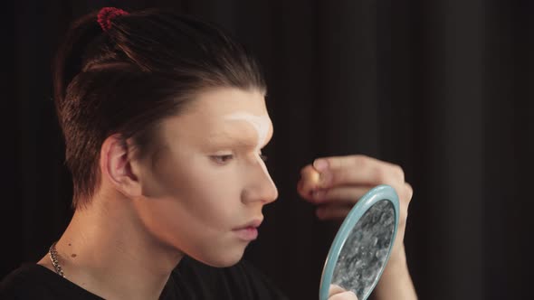 Drag Artist  Young Man Blending in the Thick Light Foundation on His Eyebrows and Forehead