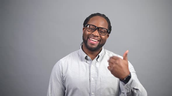 Cheerful AfricanAmerican Man Looks at the Camera and Gesturing Come Here