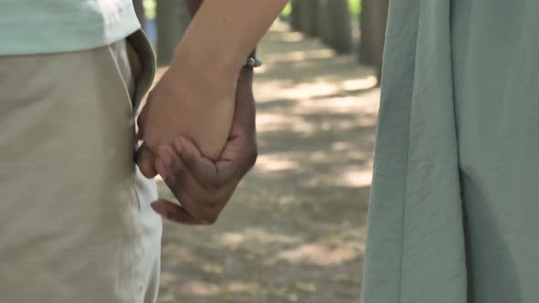 Different Races Couple Walks Joining Hands in City Park