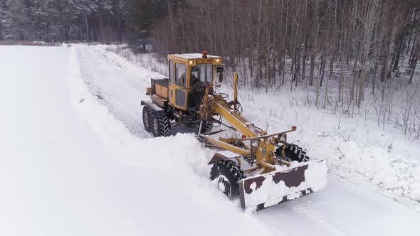 Aerial view of Snowblower Grader Clears Snow Covered Road next to the forest 14