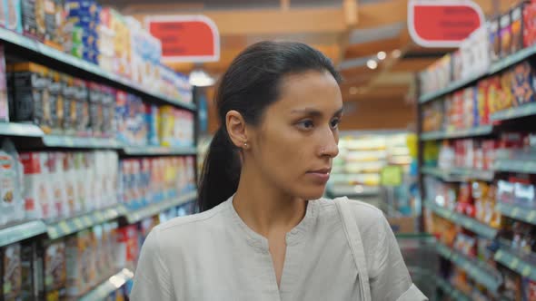 Young Mixed Race Girl Walking with Shopping Cart in Supermarket