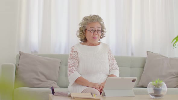 elderly asian woman using computer tablet VDO Conference online meeting with family at home