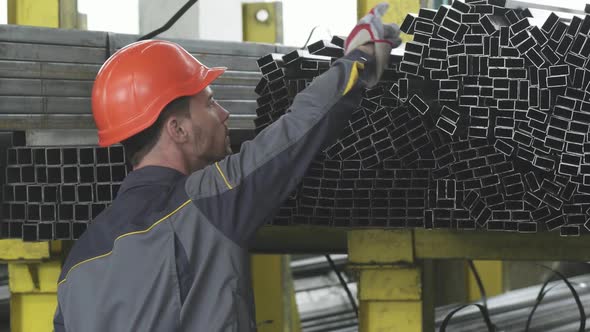 Rearview Shot of a Male Storage Worker Organizing Metal Pipes on the Shelf