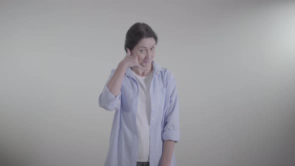 Middle Shot of Confident Woman Showing Phone Gesture and Gesturing Yes By Shaking Head. Adult