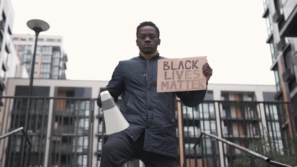 Portrait of African American Man Holds Megaphone and Black Lives Matter Carton Poster in His Hand