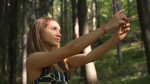 Gorgeous Fitness Girl Taking Selfie with Smartphone in the Forest