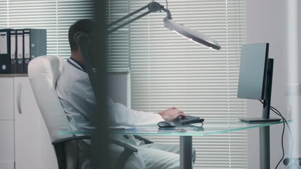 Doctor Working in His Office at the Computer