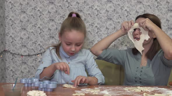 A little girl with her mother are preparing gingerbread