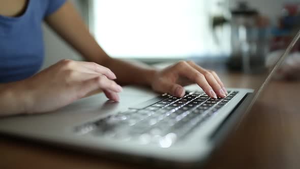 Woman typing on laptop computer at home