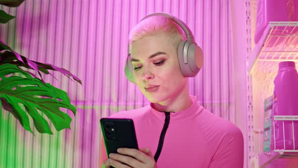 Close Up Young Woman with Short White Hair Listens to Music on Headphones and Text on Phone