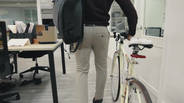 Young Businessman Arriving At Work Pushing Bicycle