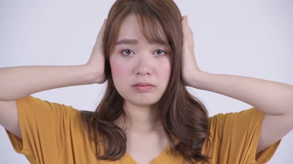 Face of Young Beautiful Asian Woman Covering Ears As Three Wise Monkeys Concept