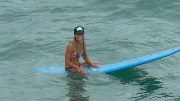 A young woman surfing in a bikini on a longboard surfboard.