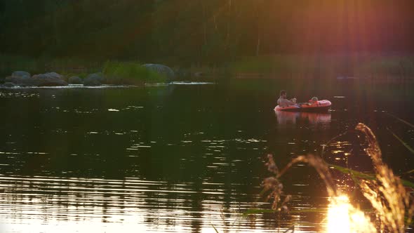 Dad and daughter having a conversation in a rubber boat on calm lake at sunrise