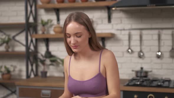 Close up beautiful young woman eating the spinach in the home kitchen with a hand.