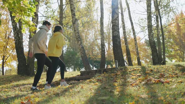 Young Man and Woman Exercising Jumping at the Park in Sunny Autumn Morning