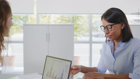 Multiethnic Female Employees Discussing Financial Charts in Office