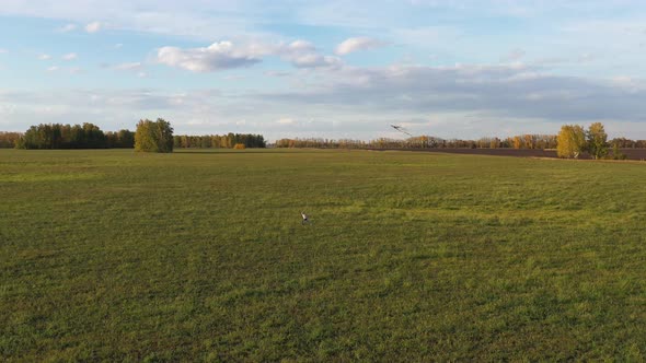 The Boy Runs with a Kite on a Green Field