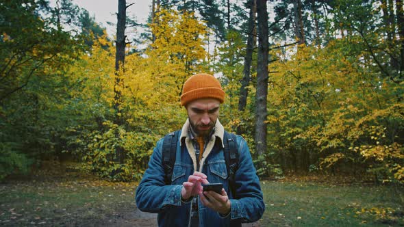 Man Traveler Trying to Catch Cell Signal on Phone Walking Alone in Autumn Forest No Signal on Mobile