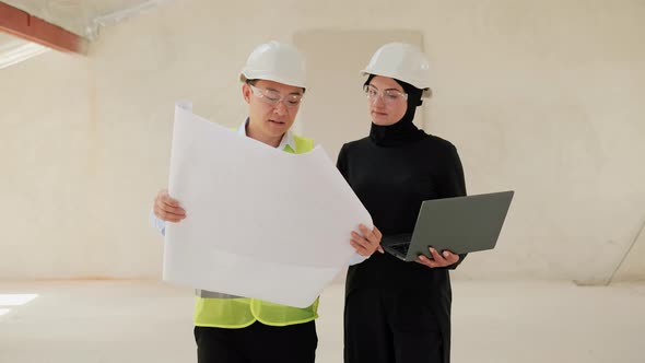 A Diverse Group of Professionals Uses a Laptop Blueprint on Construction Site