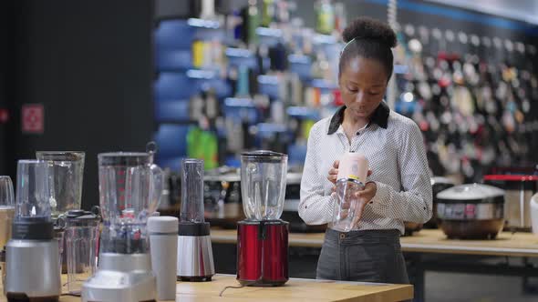 Black Housewife is Choosing Blender for Smoothies in Shop Viewing Exhibition Sample Afroamerican