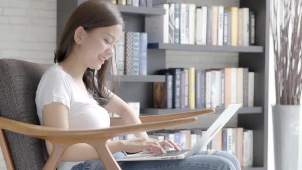 Beautiful freelance young asian woman working on laptop computer sitting on couch at living room.