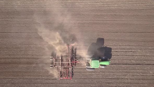 Top Down Aerial View of Green Tractor Cultivating Ground and Seeding a Dry Field
