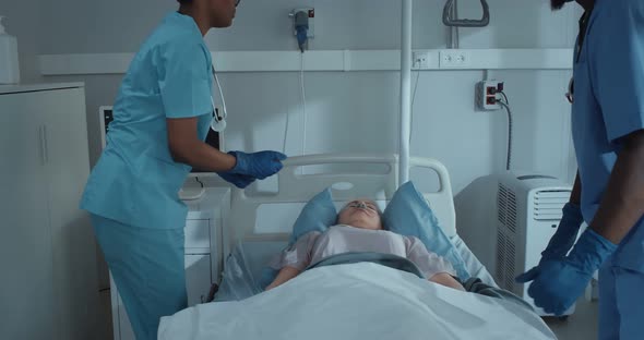 Afroamerican Medical Workers Checking Eyes of Dead Patient and Covering Body with Sheet