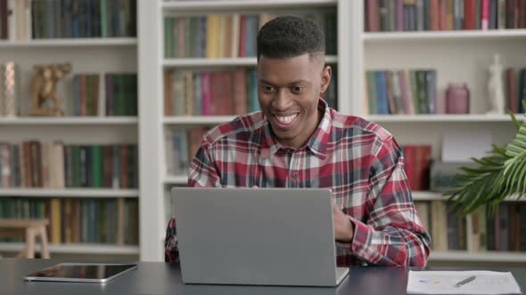 African Man Celebrating Success while using Laptop in Office