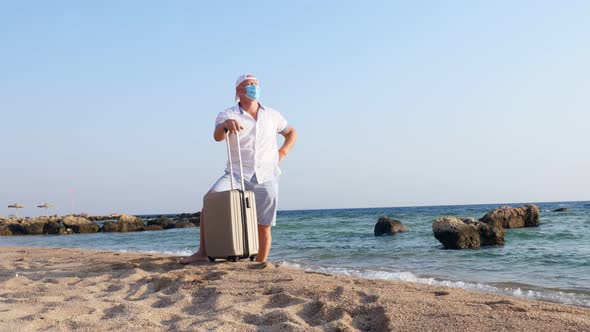 Man in Protective Mask and Summer Clothes, Enjoys Warm Sunbeams, By the Sea, Beach with Palm Trees