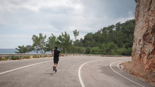 Male runner running fast on mountain road