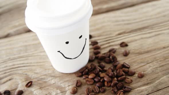 Smiley face on disposable cup with coffee beans on sack