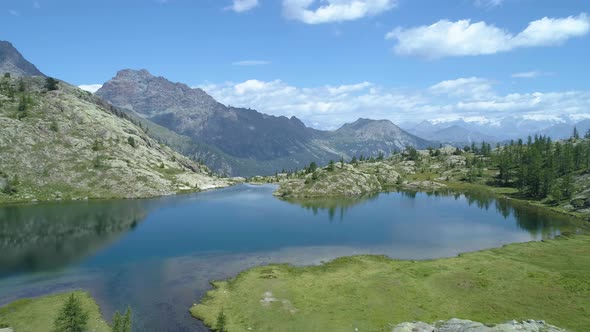 Moving Forward Above Clear Blue Lake and Pine Woods in Sunny Summer Day