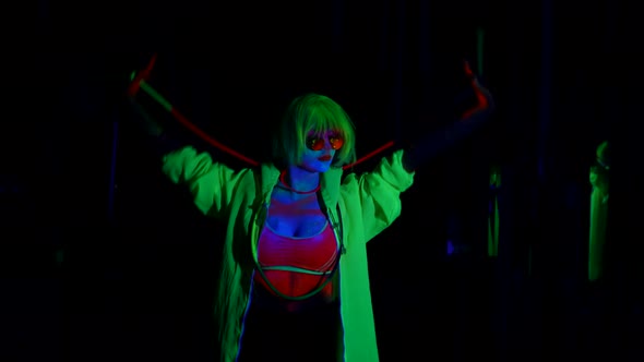 Eccentric Woman with Fluorescent Colors on Face and Neon Wig in Darkness UV Light in Nightclub