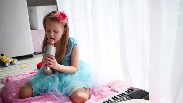 Beautiful little girl in a princess costume sings into a karaoke microphone.