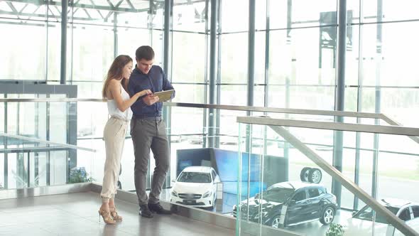 Couple Reading Car Documentation in Showroom