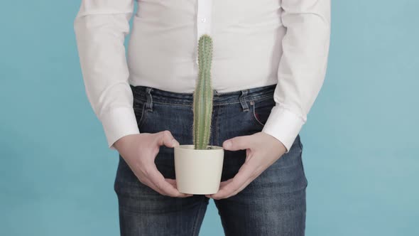 A Man Holds a Pot with a Large Cactus Against the Background of His Groin