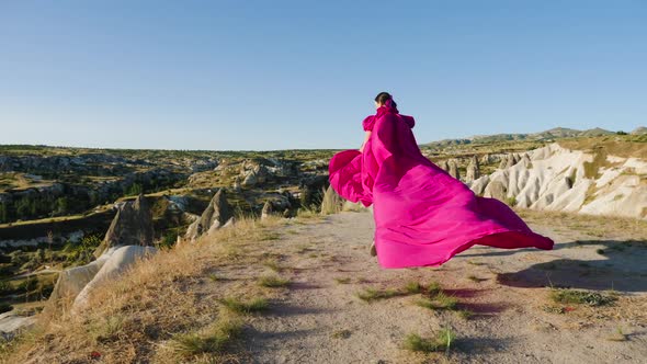 Young Tall Girl Model Runs in a Long Purple Dress with a Tail in the Mountains