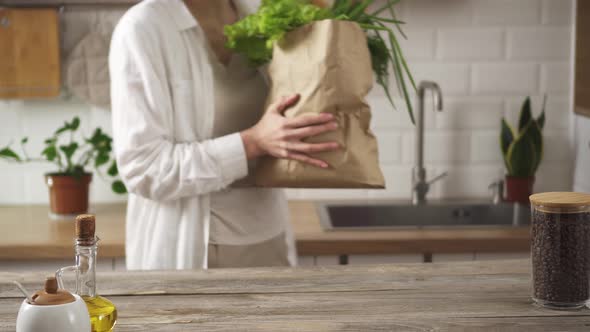 The Hostess Brought Groceries In A Kraft Paper Bag. Puts A Package Of Products On A Table Made