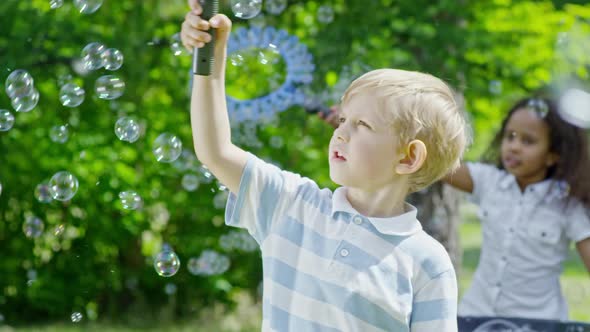 Blonde Boy Making Lots of Soap Bubbles with Wand alt