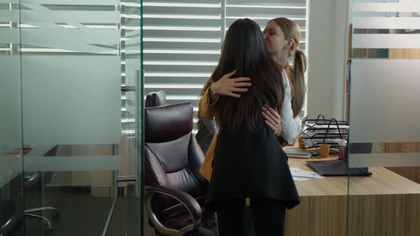 Back view of woman entering the office after a business journey hugs a coworker.